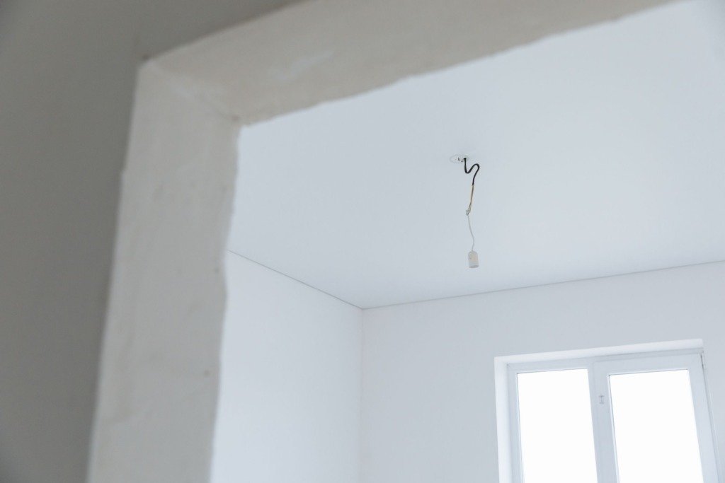 Bright white interior room with exposed electrical wiring and natural light