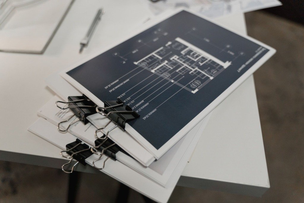 A stack of architectural floor plans bound with clips, the drawing stage of an interior design timeline in Cairo