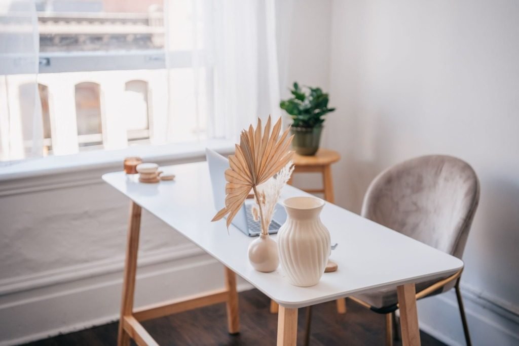 Modern office desk with a laptop and minimalist decor beside a window, remote interior design