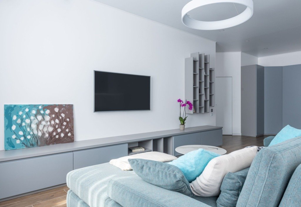 Modern interior of spacious living room decorated with gray shelves purple potted flower and picture, paint colours for a Cairo home