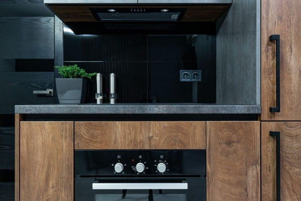 Kitchen in dark timber and stone with integrated appliances