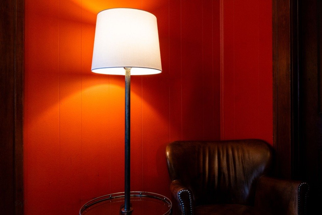 Stylish interior featuring a leather chair and floor lamp against a vibrant red wall, layered lighting for a living room in Cairo