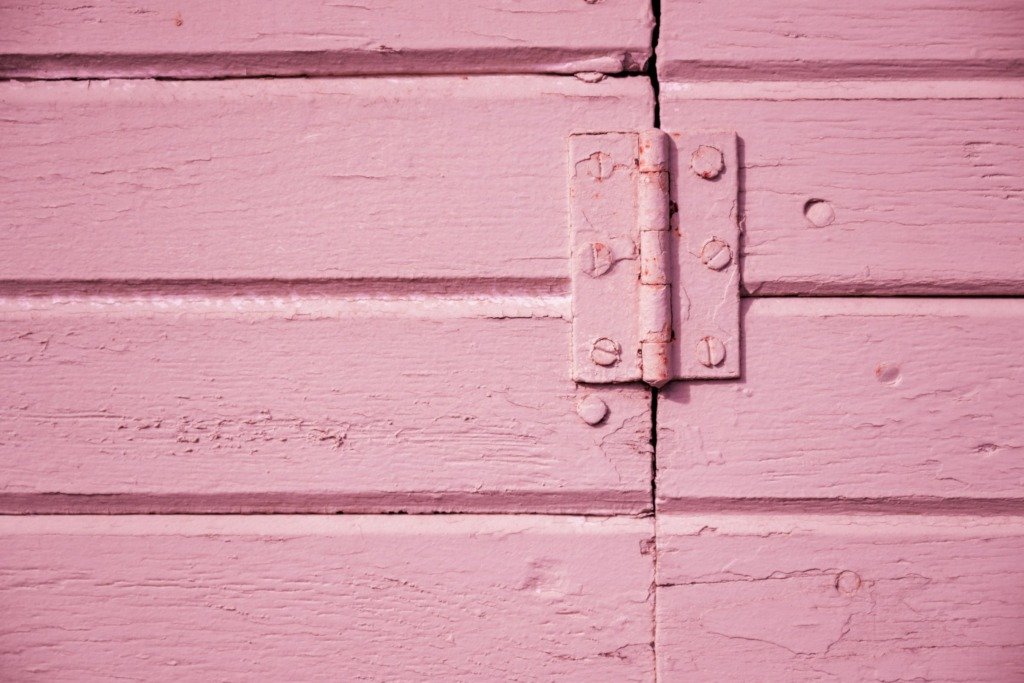 A detailed shot of a pink wooden hinge showcasing texture and color contrast.