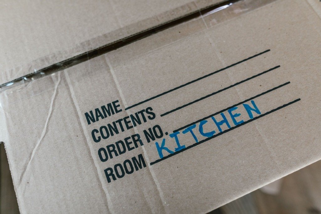 Cardboard box labeled with room destination for kitchen during moving process.