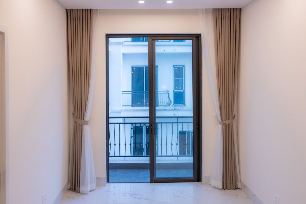 Interior view of a modern room featuring a large sliding glass door with elegant curtains.