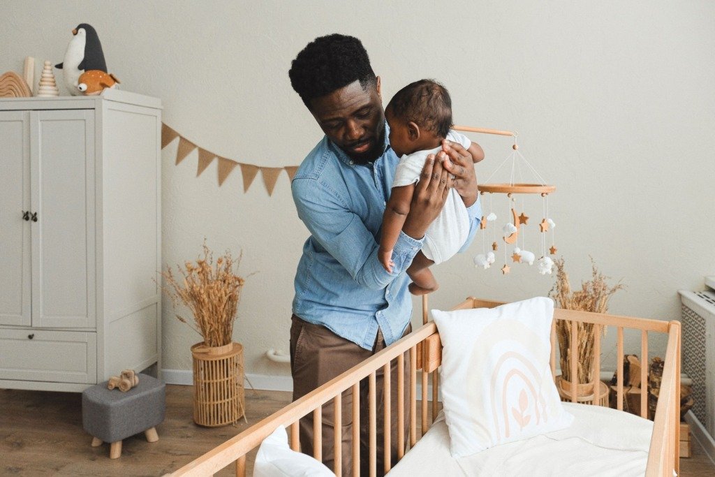 A loving father gently placing his baby in a cozy crib, showcasing familial warmth and care.